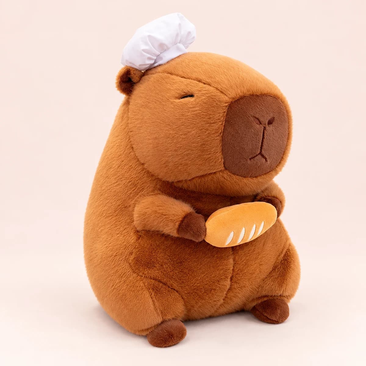 Brown capybara plush wearing a white baker hat and holding a bread loaf Brown capybara plush wearing a white baker hat and holding a bread loaf